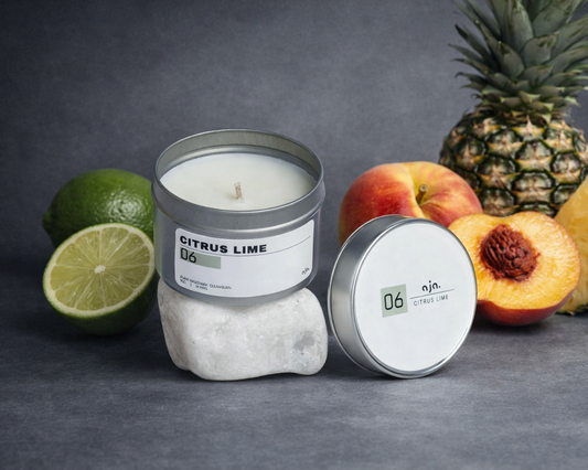 Candle with 'Citrus Lime' label, pineapple, lime, and peach on a dark background
