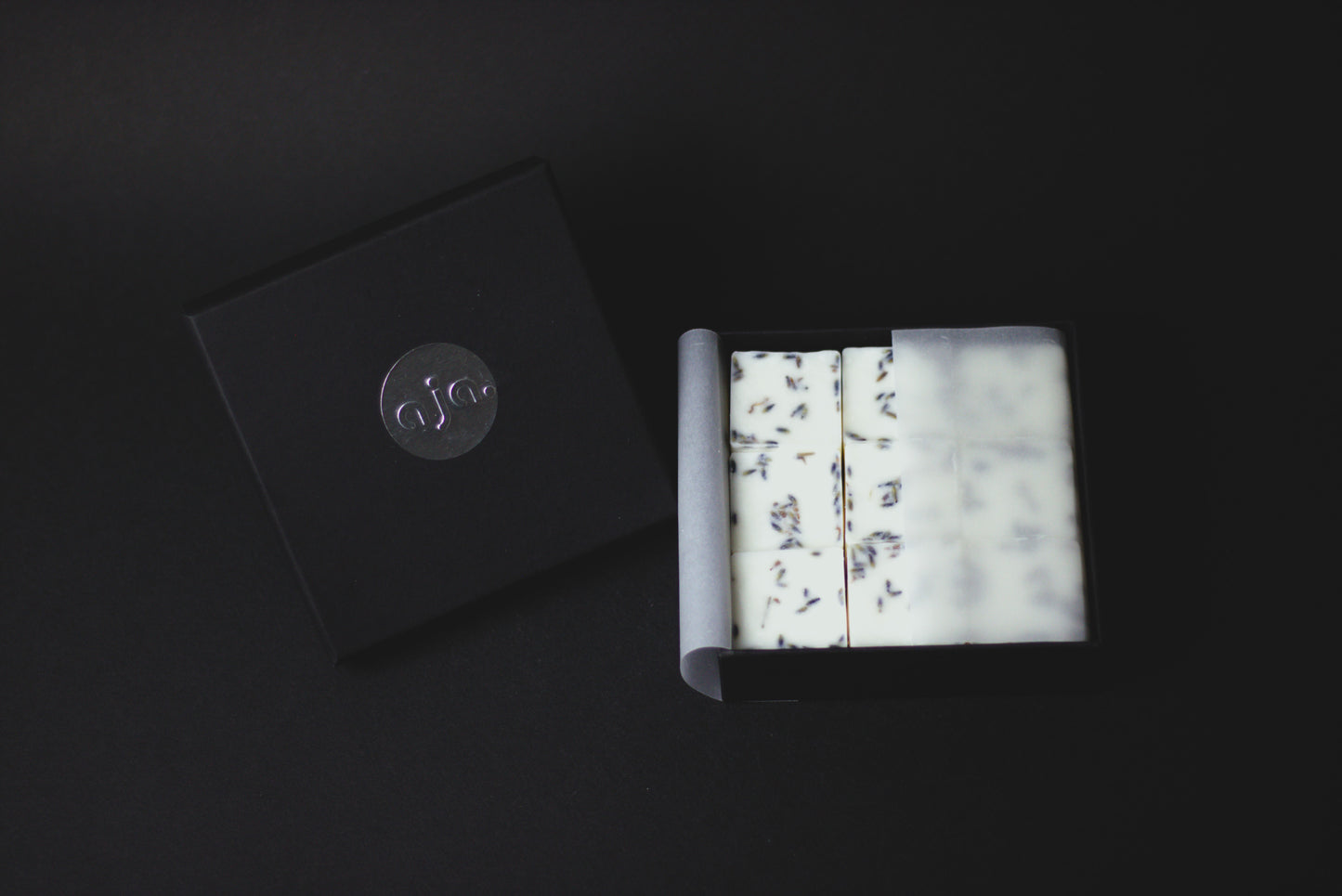 A black box with a silver logo contains botanical wax melt cubes.