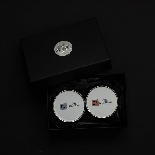 Two rscented candles in a metal tin can, black gift box on a dark background. This is a candle for selfcare with fragrance of floral freshness.