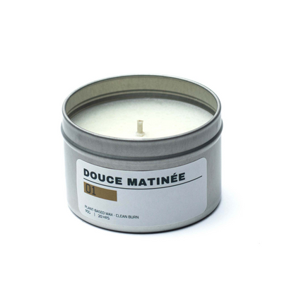 Candle in a tin labeled 'Douce Matinée' on a white background
