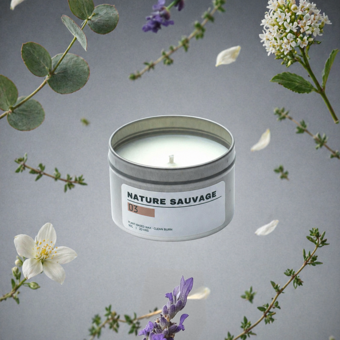 Candle in a tin labeled 'Nature Sauvage' surrounded by floating flowers and leaves on a gray background