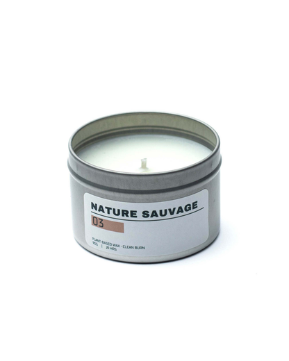 Candle in a metal tin labeled 'Nature Sauvage' on a white background