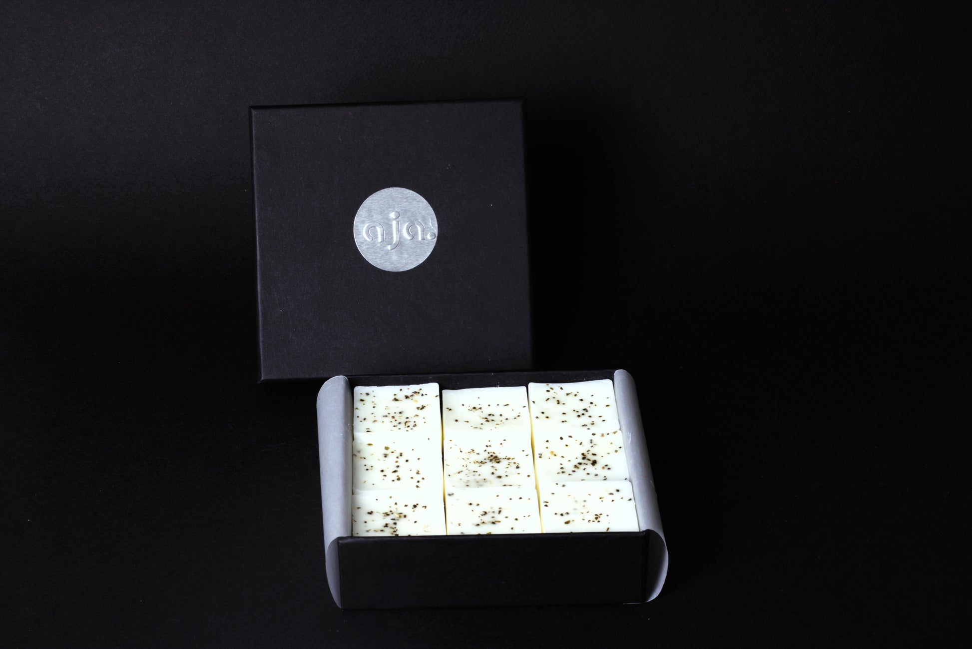 A black box with a silver logo contains botanical wax melt cubes.