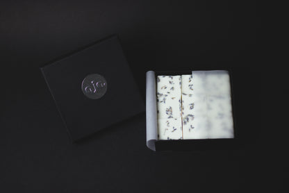 
A black box with a silver logo contains botanical wax melt cubes.
