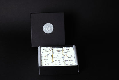 A black box with a silver logo contains botanical wax melt cubes.
