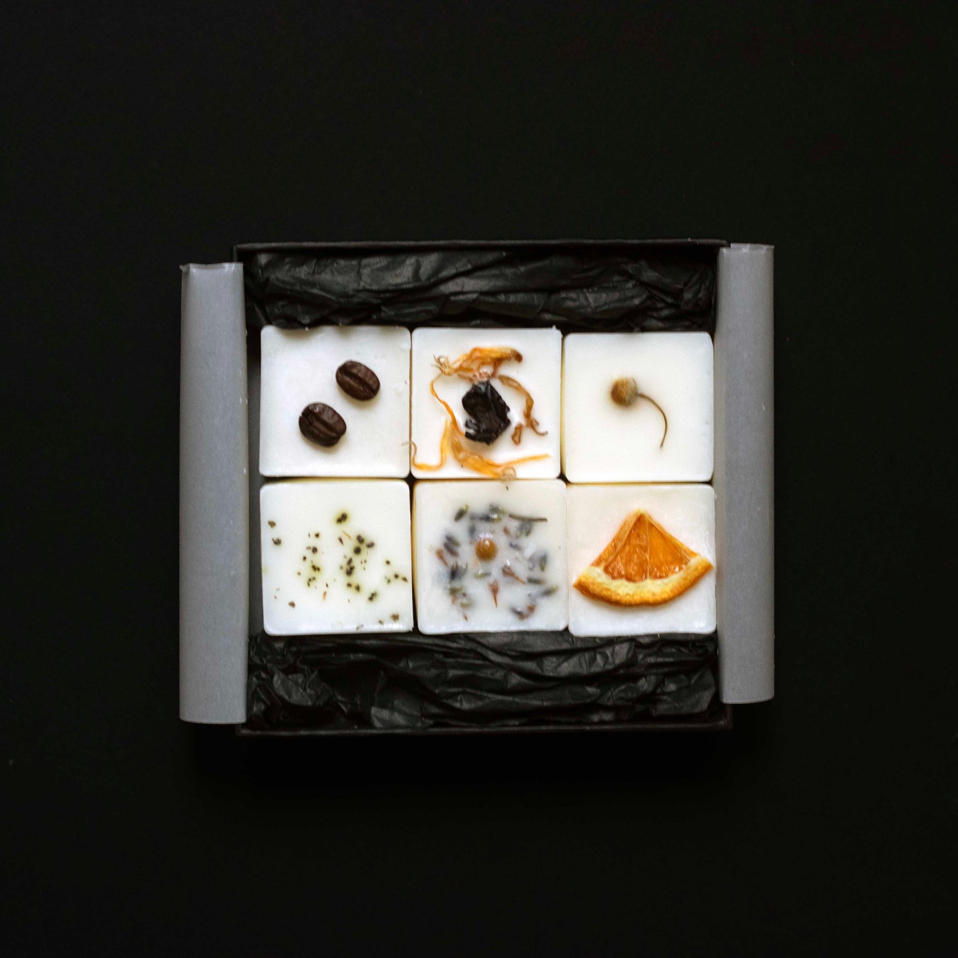 Six wax melts cubes arranged in a square grid on a black background
