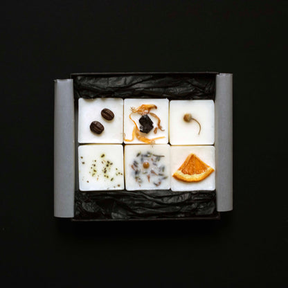 Six wax melts cubes arranged in a square grid on a black background