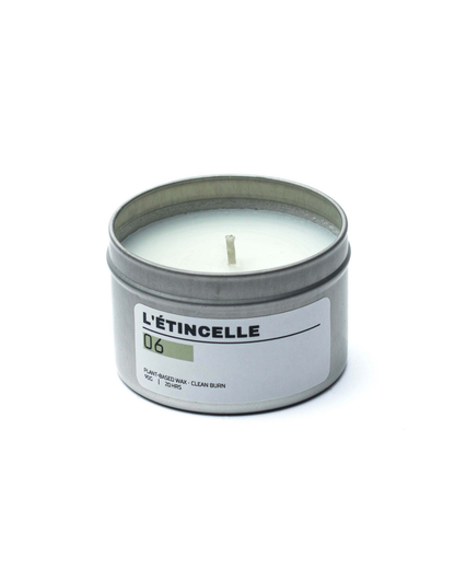 Candle in a tin labeled 'L'étincelle' on a white background