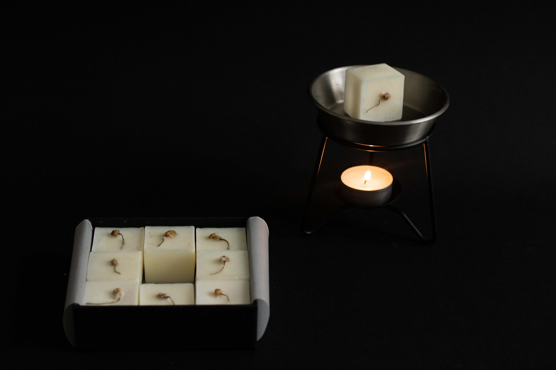 Candle melts into a small dish with a box of wax cubes on a black background
