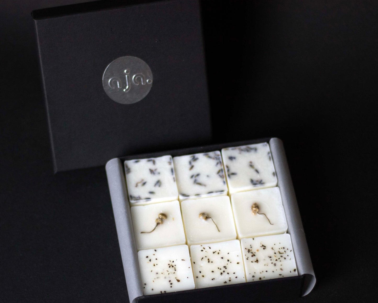 Box of scented wax melts with botanicals on top on a black background