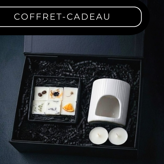 Gift set with a white candle and small items in a black box on a dark background